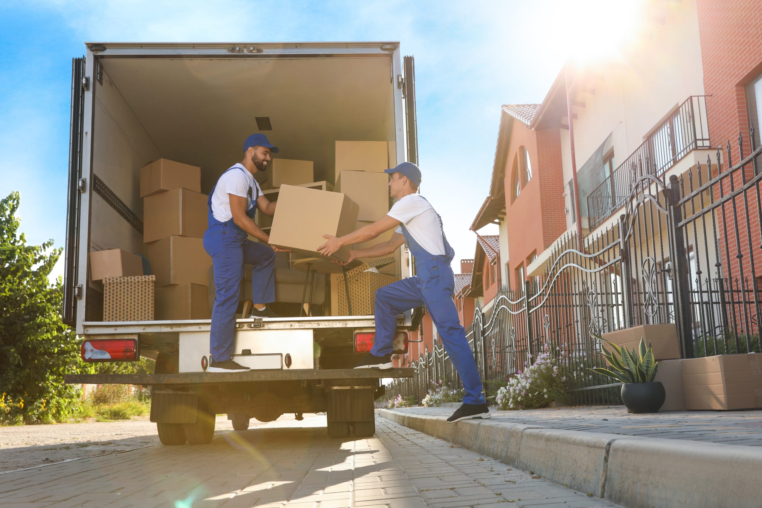 Moving professionals carefully carrying packed boxes and household furniture